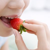 いちごを口に運ぶ女性